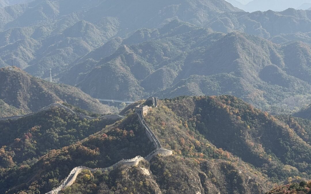 The Great Wall of China winding along forested mountain ridges in autumn