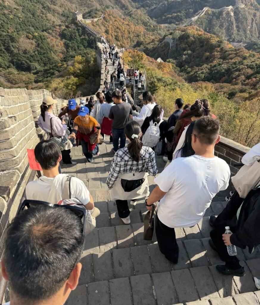 Visitors walking down steep stone stairs on the Great Wall of China in autumn